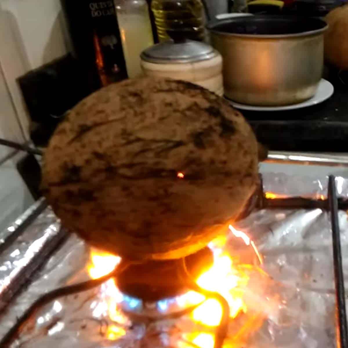 queimando o coco na boca do fogao
