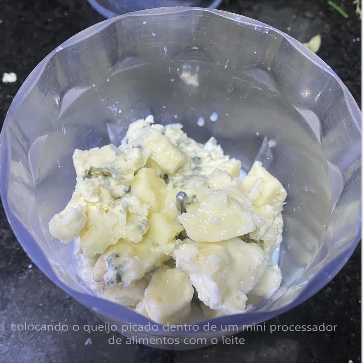 colocando o queijo picado dentro de um mini processador de alimentos com o leite